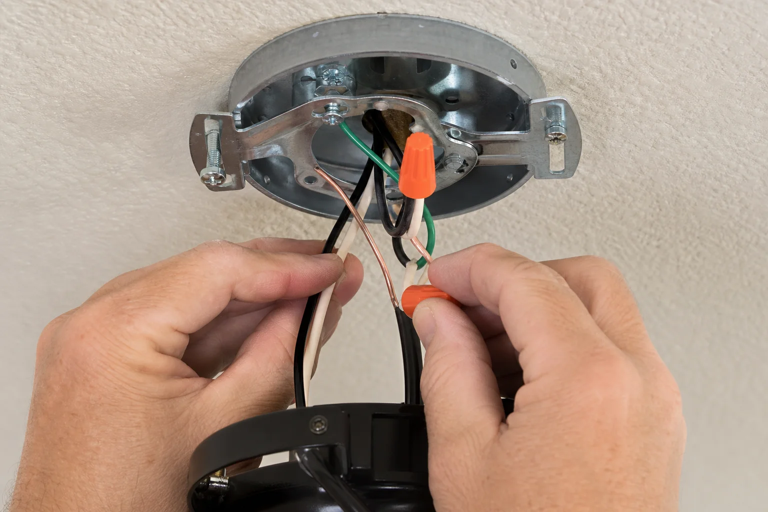 Close up of a licensed Kansas City electrician connecting wiring to a new fan rated ceiling box during a ceiling fan installation